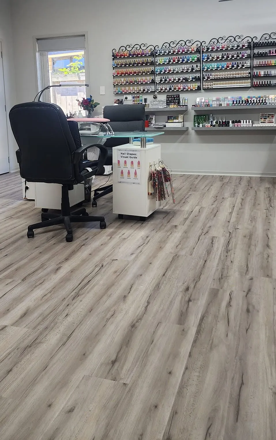 Inside the salon: a nail desk with a black chair, and a wall of colourful polish shelves