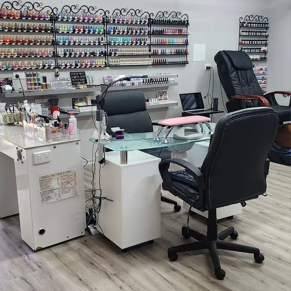 The nail desks and pedicure chair in front of the polish wall